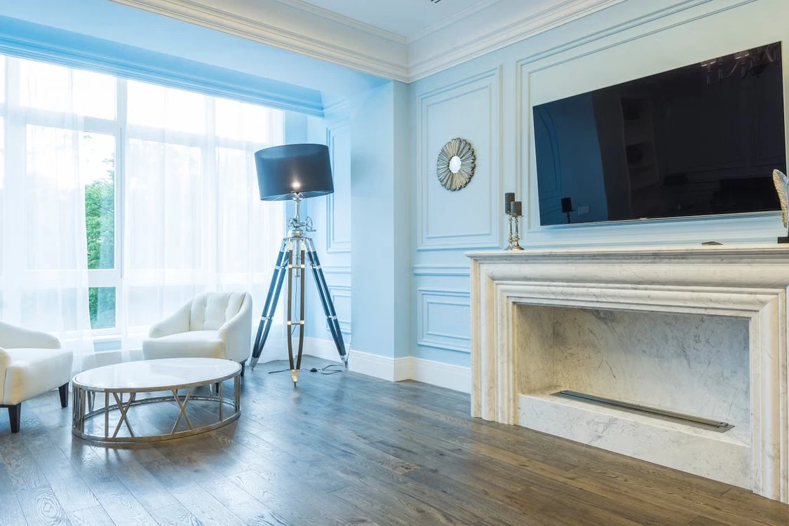 Inspiratiebeeld van een lichte woonkamer met blauwe wanden, sierlijsten en een houten vloer