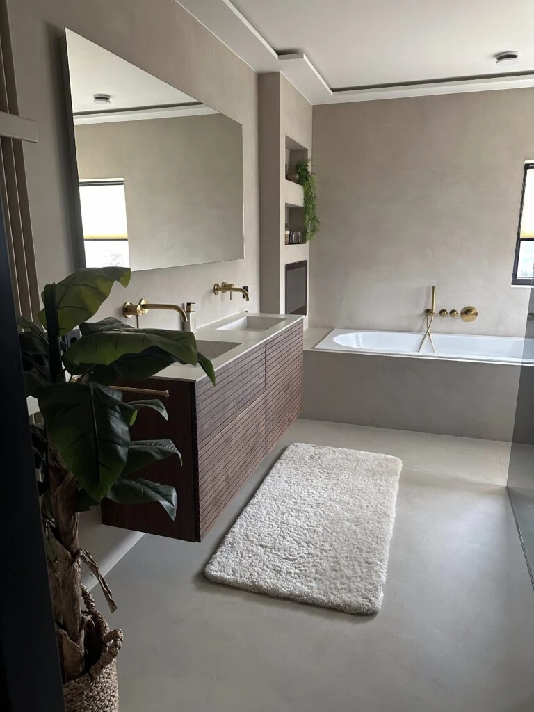 Badkamer van Looman met bad, wastafelmeubel en gouden kranen