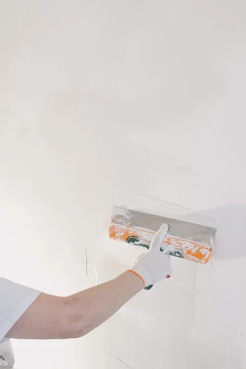 Close-up van een stukadoor die een wand glad afwerkt